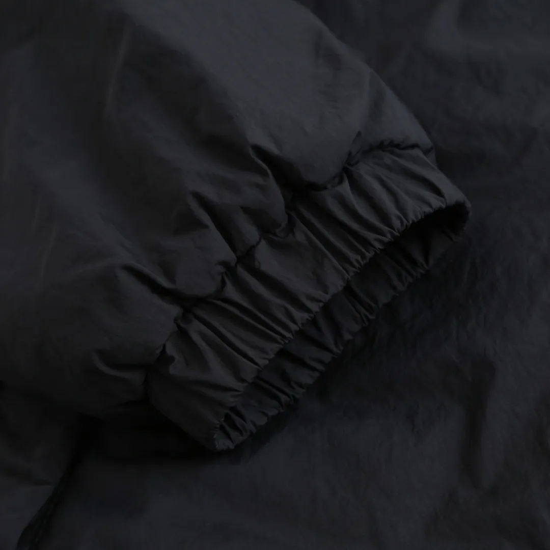 🅿️680 Ralph Lauren pony embroidered light cotton jacket. The fabric is made of high-density nylon taffeta fabric, which combines pragmatism and classic texture. The density is about 210T-300T, the surface is smooth and slightly matte, it has excellent windproof and waterproof performance (with DWR water-repellent treatment), it has strong wrinkle resistance and is easy to care for, which is in line with the positioning of American casual "durable and practical". Classic dark black, using vat dyeing process (dye penetrates into the fiber), the color fastness reaches ISO level 4 or above, preventing fading or color transfer after washing. The lining is made of light cotton-polyester blended fabric (65% Polyester + 35% Cotton) to reduce the friction between the fabric and the inner clothing and improve the smoothness of wearing; the blended material has both breathability and durability to avoid the stuffy feeling of pure nylon lining. The style is a loose fit of the classic Coach Jacket, with slightly dropped shoulder lines (shoulder width is 1-2cm wider than the standard fit). The length reaches the hips, and the sleeves are slightly tapered straight sleeves, taking into account both freedom of movement and casual style. The Polo horse logo on the left chest is flat satin stitch embroidered (satin embroidery), embroidery thread: 100% polyester high color fastness embroidery thread (the color number is consistent with the brand’s standard red color card), the stitch density is 12-15 stitches/cm, the outline of the horse logo is clear, and the details of the rider and horse are burr-free. The embroidery is positioned accurately through the template (12cm from the bottom of the neckline and 8cm from the placket) to ensure left-right symmetry and centering. The seams of the body are made of double-needle flat seams (needle pitch 3cm/10 needles), the stitches are flat and straight, the stitching color is dark black (the same color as the fabric), and the stitch width is 0.5cm, which enhances firmness while forming simple decorative lines. The front placket is spliced ​​with the body. The placket is made of double-layer folding + flat seam splicing. The thickness is about 0.3cm to ensure that the buttons are not easily deformed when fixed. The edges of the placket are cut with a hot knife to avoid burrs. The armholes where the sleeves and body are joined are made with round-head keyhole machine seams + flat seams. After the splicing, the armholes have a natural curvature and no sense of tightness during movement. The height of the sleeves is about 8-10cm, which is in line with the loose characteristics of casual jackets. The main buttons are made of black urea resin buttons with a matte surface. The buttonholes are hand-made keyholes (6 strands of cotton thread, keyhole density of 8 stitches/mm), and the edges of the eyelets are smooth and without burrs. The first button on the neckline is a hidden button (diameter 12mm), which prevents the neckline from opening and improves the neatness of wearing. Size:S-M-L-XL